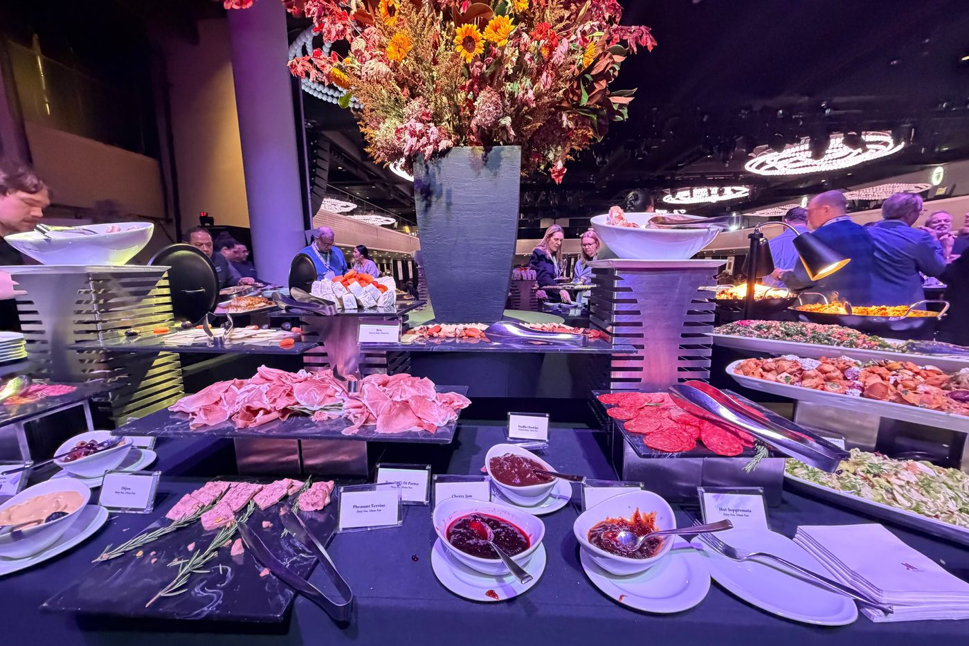 A spread of charcuterie and small plates beneath a towering autumn floral arrangement